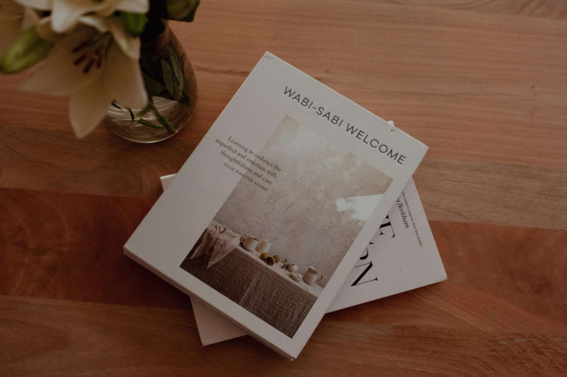 Wabi-Sabi Welcome book on table near vase with flowers