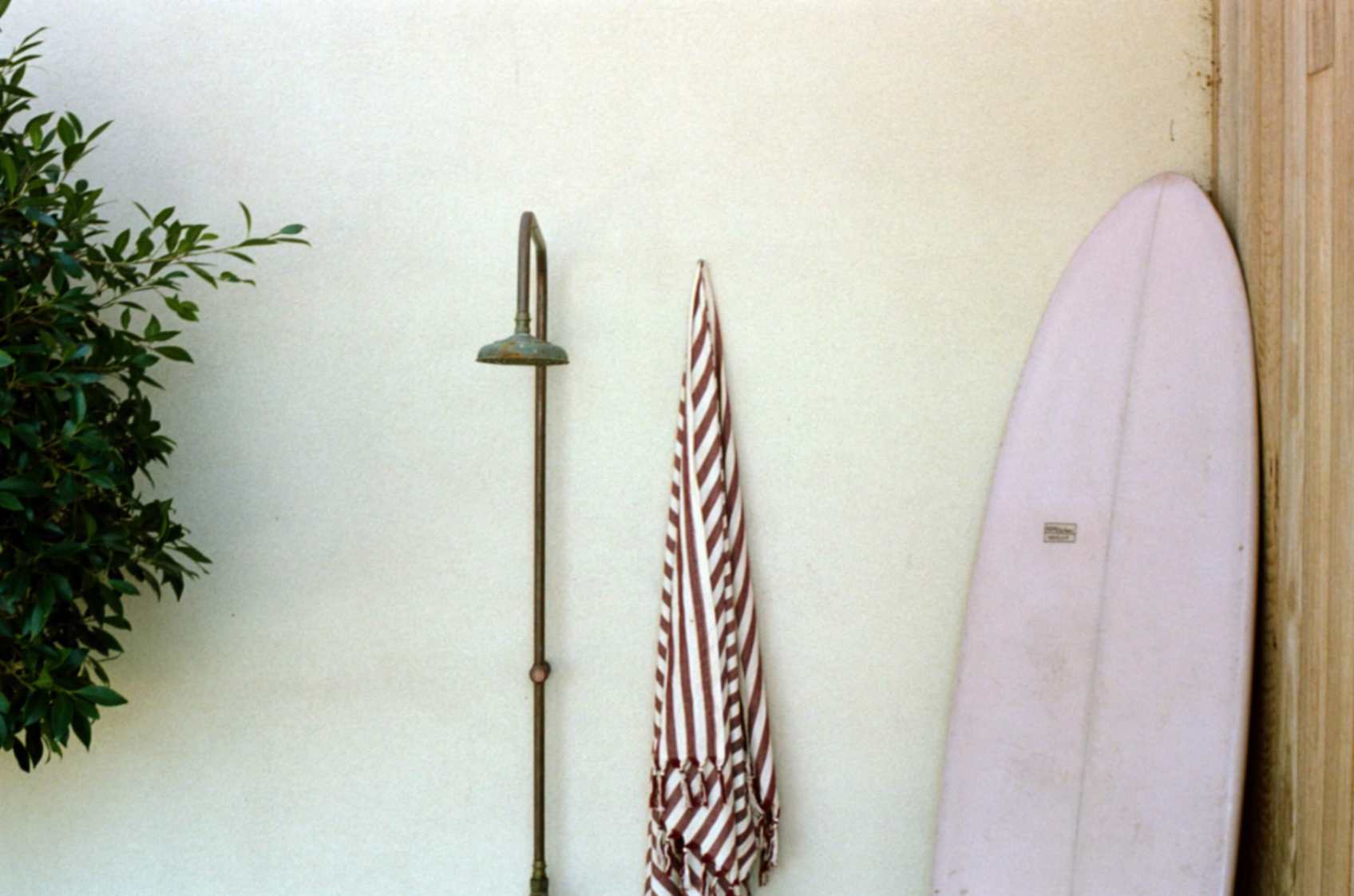 Surfboard and folded umbrella leaning on wall at this Merimbula accommodation