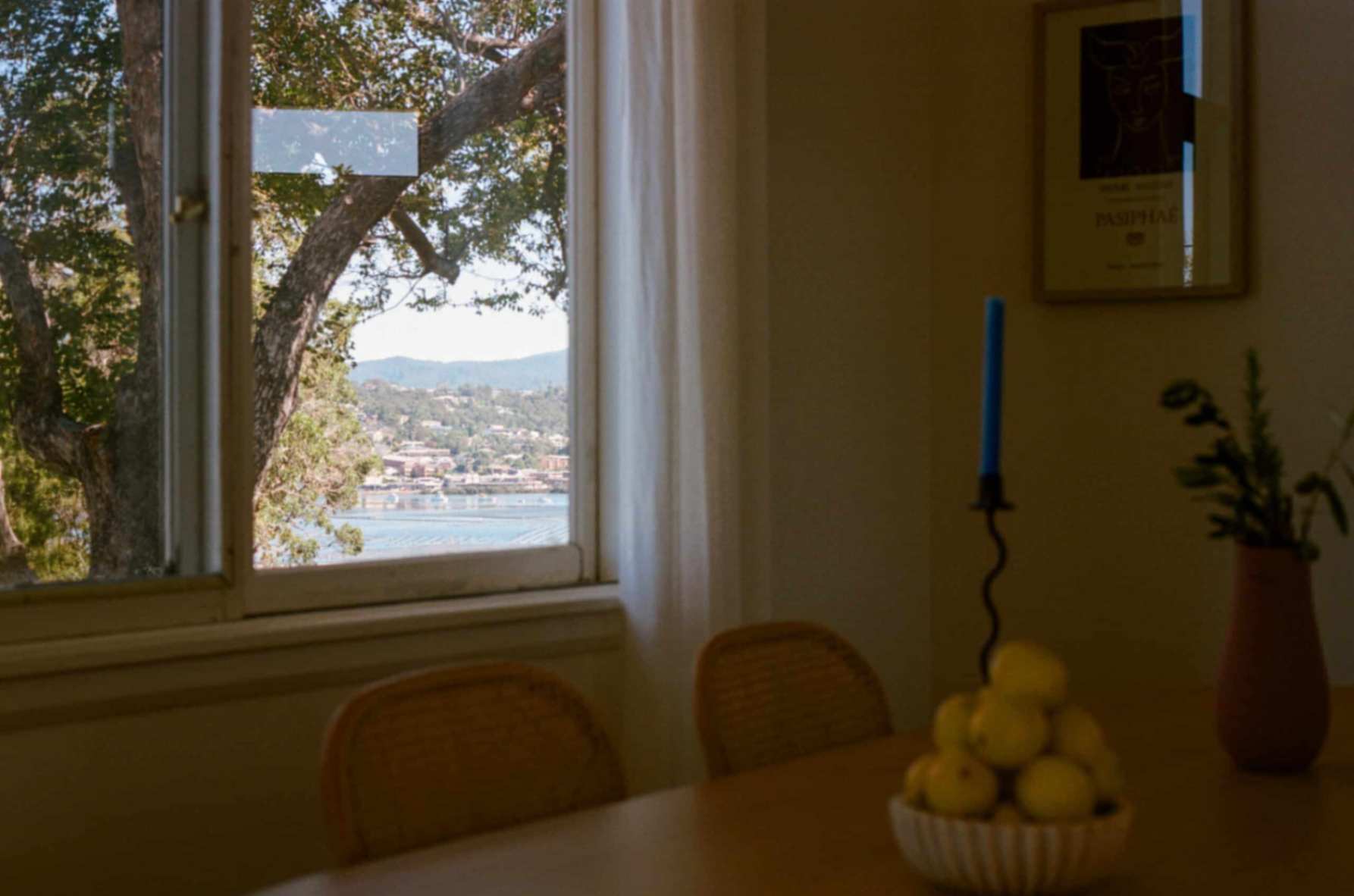 Interior with bowl of fruit on table with chairs in Doma Short Point, A Merimbula Holiday Rental. Beach view and tree from window