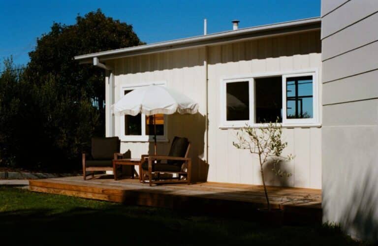 Backyard of Doma Short Point Merimbula Holiday accommodation, with chairs and small table under umbrella